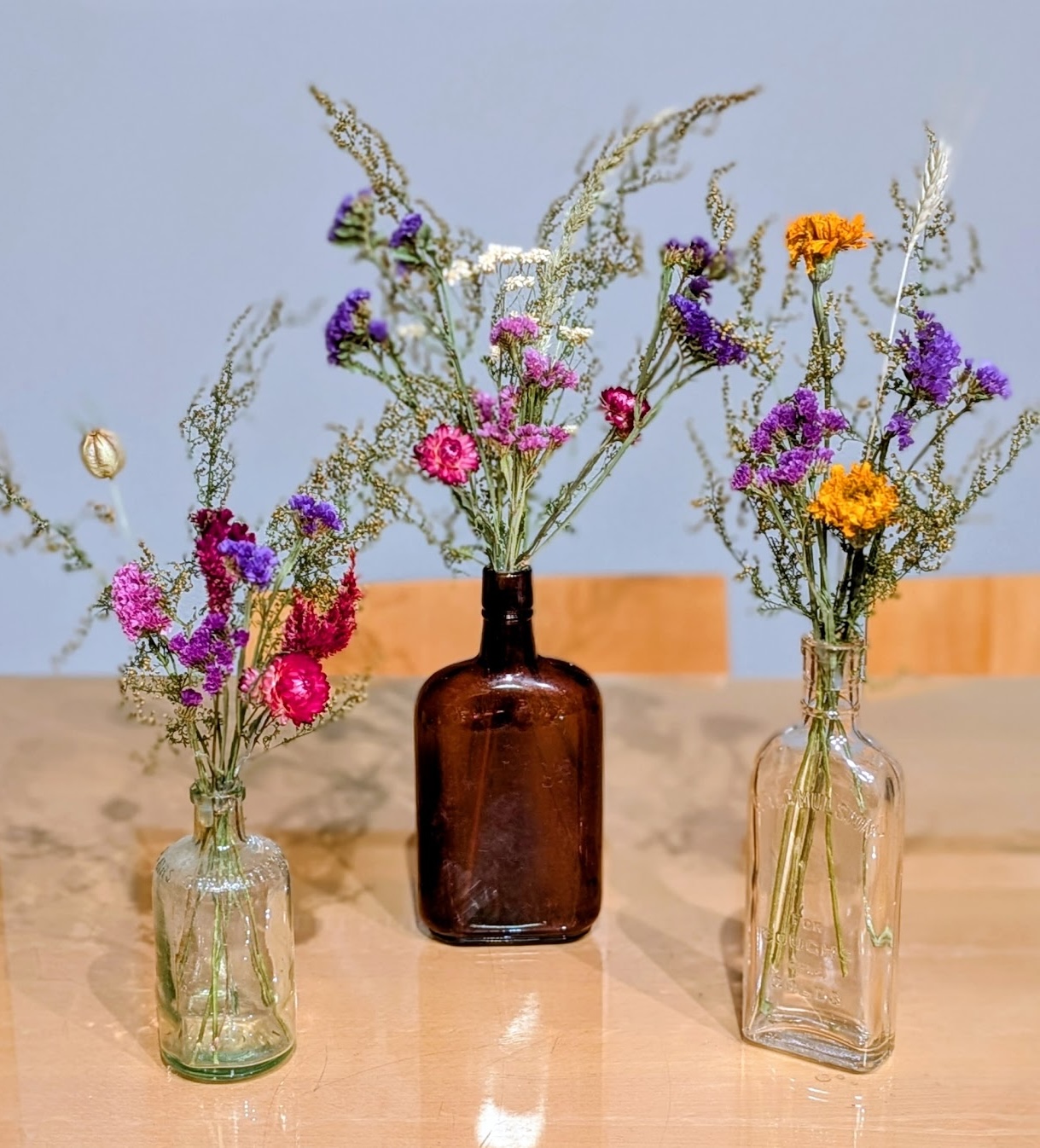 Dried wildflowers in mismatched vintage glass bottles