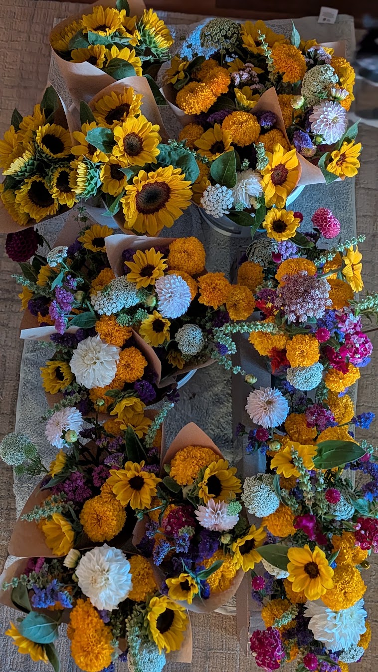 Paper-wrapped bouquets of sunflowers, marigolds, and late-summer blooms