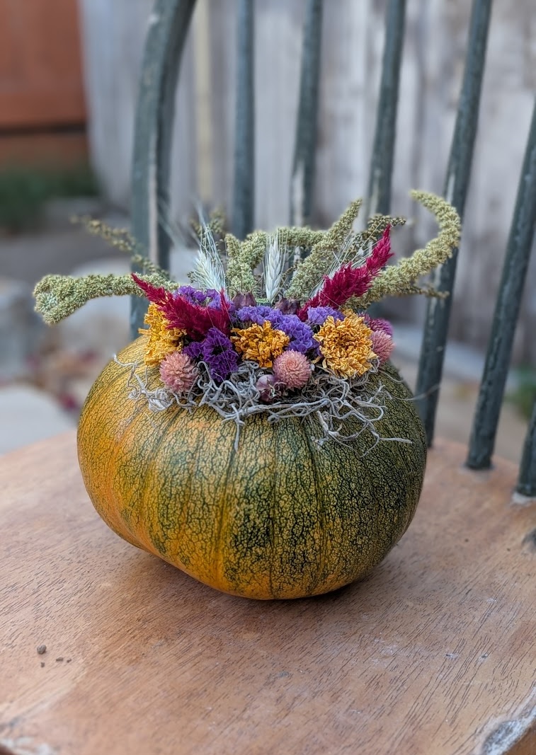Dried flowers arranged in a small green and orange pumpkin